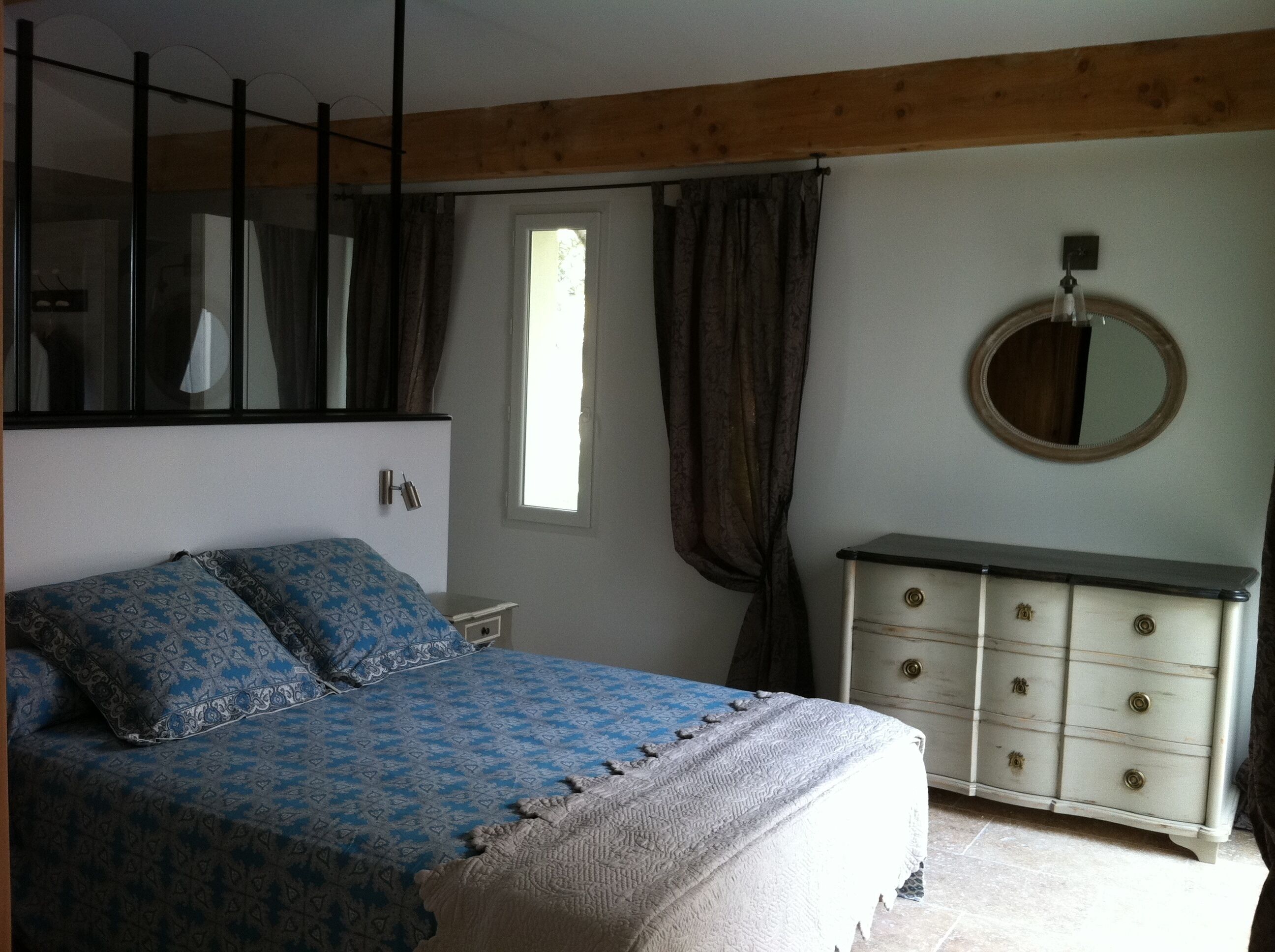 Un dormitorio con cama, cómoda, espejo y ventana.