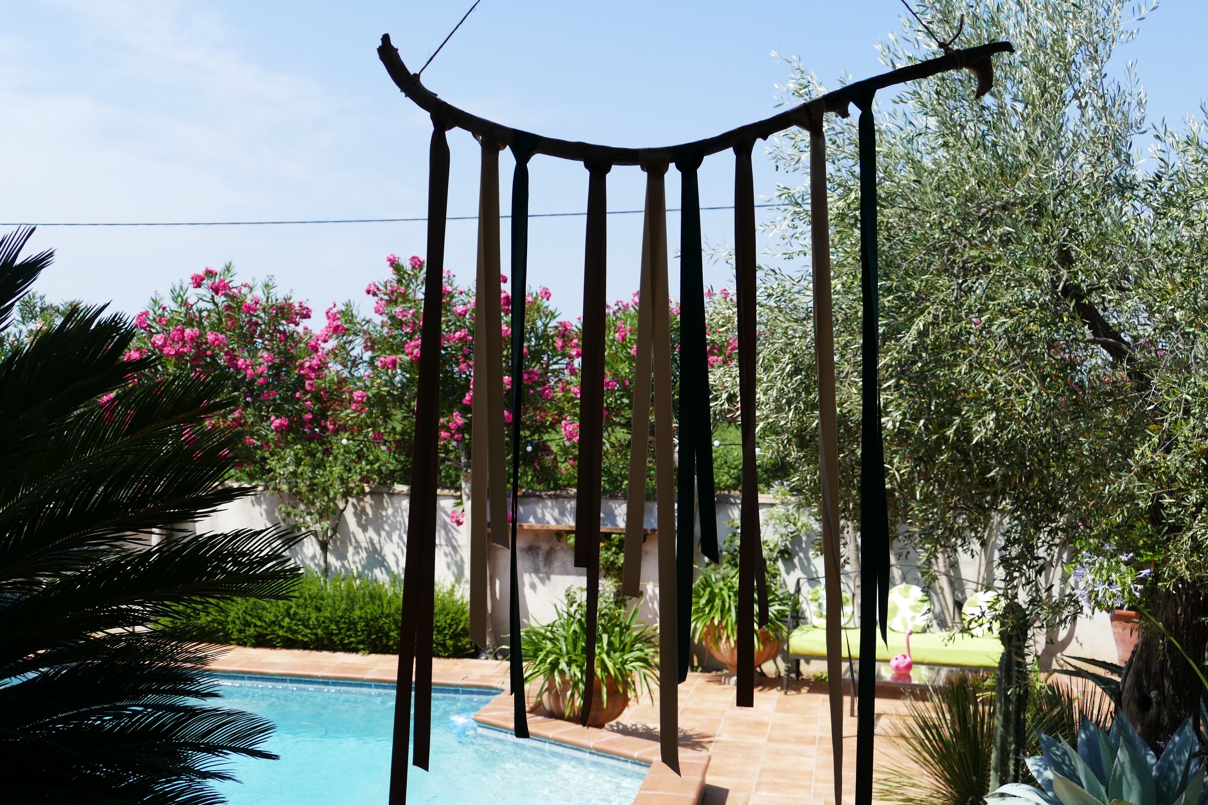Ett poolområde med en pergola, omgivet av frodig grönska och blommande växter.