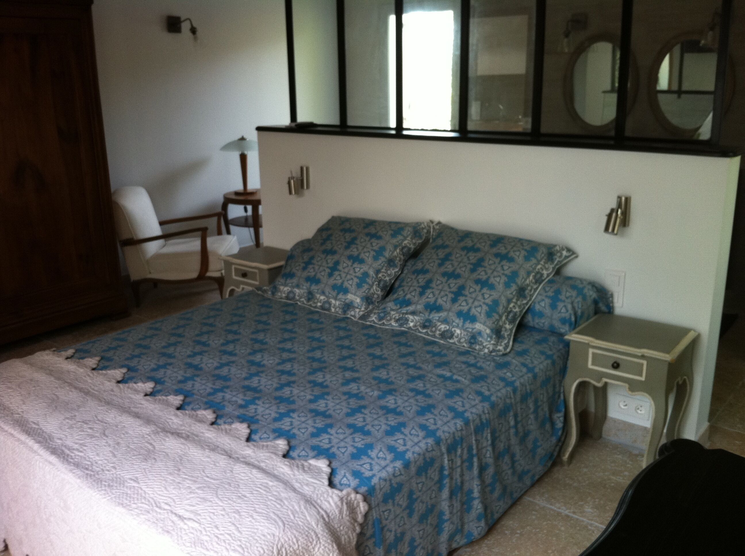 Un dormitorio con cama, una silla, una mesita de noche y un aparador.