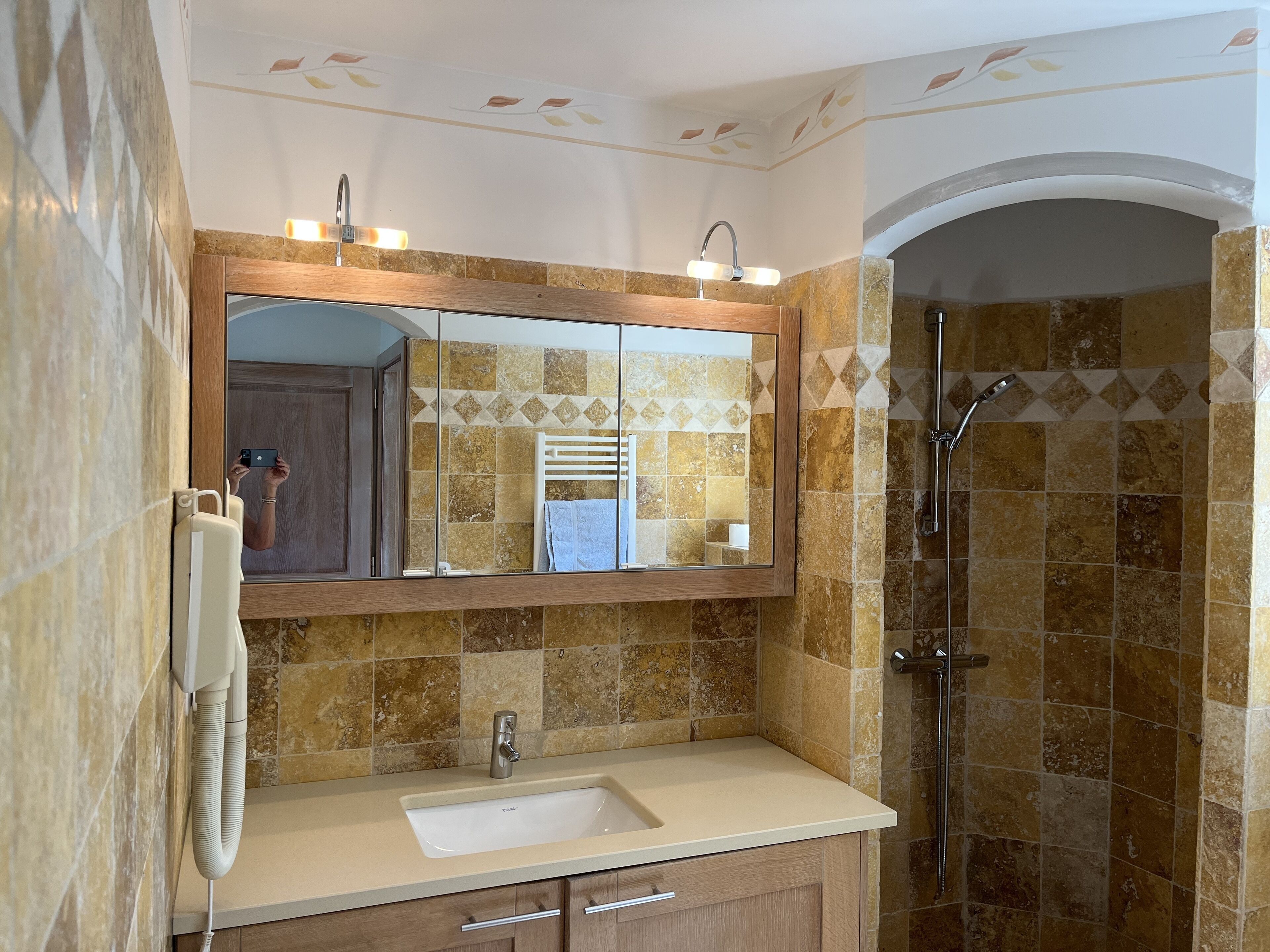Une salle de bain avec un grand miroir, un lavabo, un porte-serviettes et un espace douche.