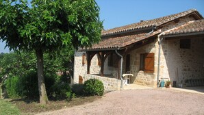 Un bâtiment en pierre avec un toit en tuiles, un porche abrité et une allée gravillonnée.