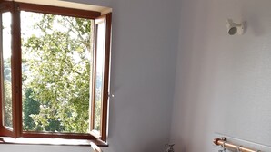 Une chambre à coucher comprenant un lit, une chaise, une table de chevet, un radiateur et une fenêtre.