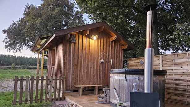 A wooden cabin with a hot tub, a bench, and a wooden fence. - Gîte rural des Gravets, shared pool (Sigalens)