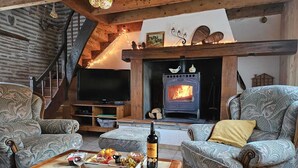 A cozy living room with a fireplace, wooden furniture, and a television. - Gîte rural des Gravets, shared pool (Sigalens)