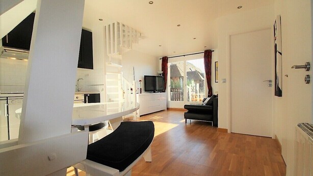 A modern living room with a white sofa, a television, and a dining area with a white table and chairs. - COUP DE ❤️ LA MOUETTE DEAUVILLAISE🐦classified 4☆ Tennis-Pool-Parking-Linen-Wifi (DEAUVILLE)