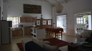 Un'ampia zona giorno con cucina, tavolo da pranzo e una grande finestra.