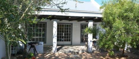 A house with a covered patio, a swimming pool, and potted plants.