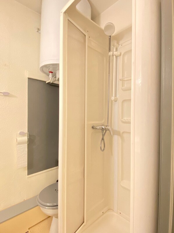 A bathroom with a toilet, a shower, and a towel rack.