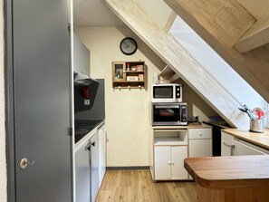 Une cuisine compacte équipée d’un four à micro-ondes encastré, d’un petit four et d’une horloge murale.