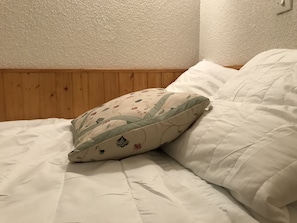A bed with a floral pillow and a plain white pillow.