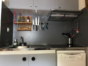 A kitchen with a stainless steel sink, a dish rack, and a dish soap dispenser.
