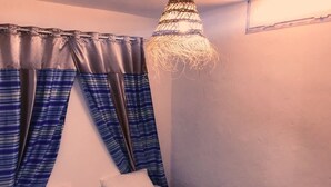 A bedroom with a bed, two pillows, a blue and red striped blanket, and a hanging light fixture. - Dar AESHA (Without Vis à Vis) (Djerba)