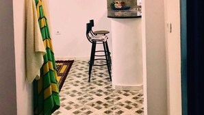 A narrow hallway with a tiled floor, a towel rack with a towel, a chair, and a small table with items on it. - Dar AESHA (Without Vis à Vis) (Djerba)