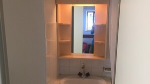 Ein Badezimmer mit Waschbecken, Spiegel und Mülleimer.
