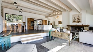 A spacious living area with a fireplace, wooden beams, and a large window overlooking greenery. - Magnificent villa of 260m2 air-conditioned sea view heated swimming pool and beach on foot (Olmeto)