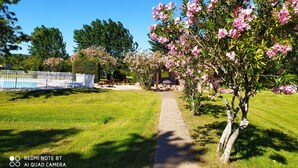 A garden with a pathway, picnic tables, and a fenced swimming pool area. - Duplex for 5 people, 500m from the beach in a residence with swimming pool (Sainte-Lucie de Porto-Vecchio)