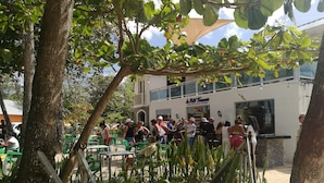 Un espace extérieur aménagé avec des tables et des chaises, un bâtiment avec une enseigne et des arbres.