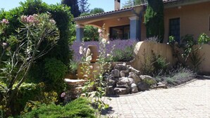 Ein Garten mit einem 'Feel Home' Schild, einem Steinweg und einem Gebäude mit Ziegeldach.