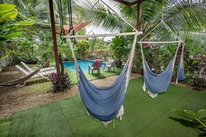 Ein Poolbereich mit zwei Hängematten, einem Pool und einer überdachten Sitzgelegenheit mit Stühlen.