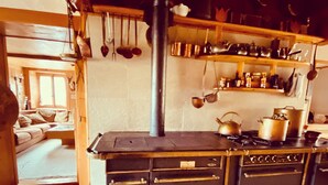A kitchen with a stove, oven, and various cooking utensils. There is a wooden cabinet with drawers and a countertop. - ✨CHALET WITH A CINEMATIC VIEW  (Ormont-Dessus)