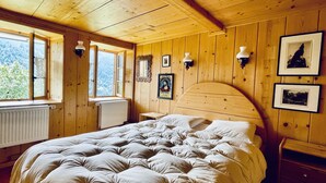 A wooden room with a bed, a radiator, and framed pictures on the wall. - ✨CHALET WITH A CINEMATIC VIEW  (Ormont-Dessus)