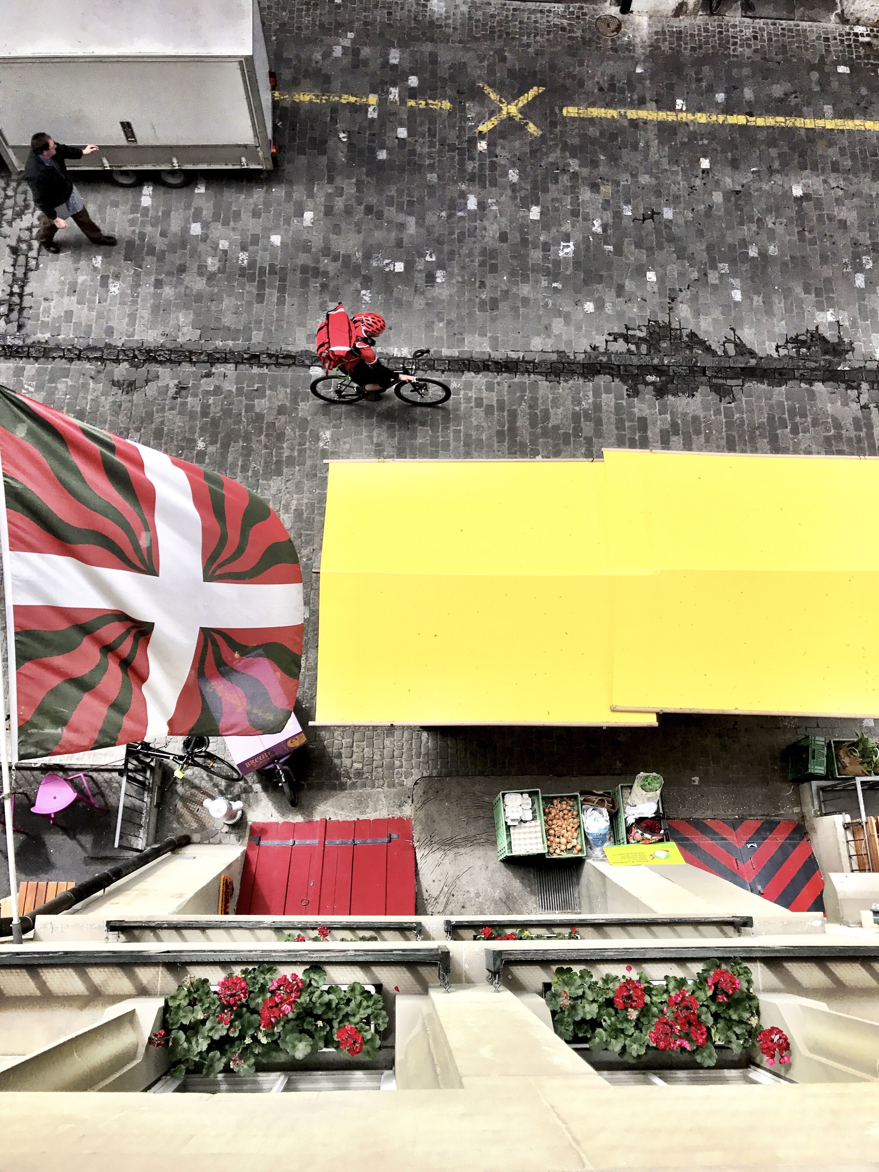 Vista de la calle con una bandera grande, un toldo amarillo y una puerta roja.