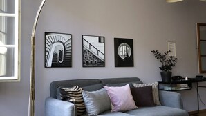 A modern living room with a grey sofa, a floor lamp, and three framed pictures on the wall. - Sunny Old Town Flat •  Walk Everywhere • Sleeps 4 (Bern)