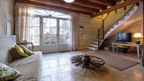 A cozy living room with a sofa, a coffee table, a television, and a staircase leading to an upper level. - La Treille du Mas Vacation Rental—3-Star Rating (Arles)