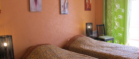 A room with two beds, a chair, and a lamp.