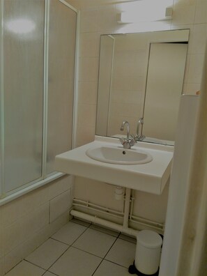 A small bathroom with a white sink, mirror, and toilet.