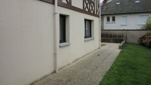 Un immeuble résidentiel avec une allée étroite, un petit jardin et une fenêtre bien visible.