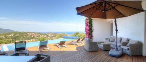 A wooden deck with outdoor furniture, a pool, and a view of the landscape.