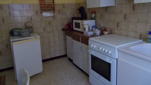 Una cucina compatta con frigorifero, microonde, piano cottura e un piccolo lavandino.