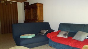 Un soggiorno con un divano blu, una coperta rossa e un tavolino rotondo.
