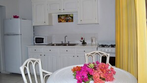 Une cuisine avec des meubles blancs, un four à micro-ondes, un évier, une cuisinière et une table à manger agrémentée d’un arrangement floral.
