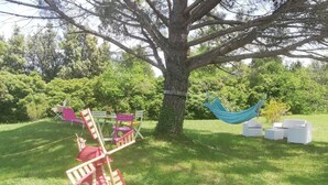 A tree with a hammock and outdoor furniture.