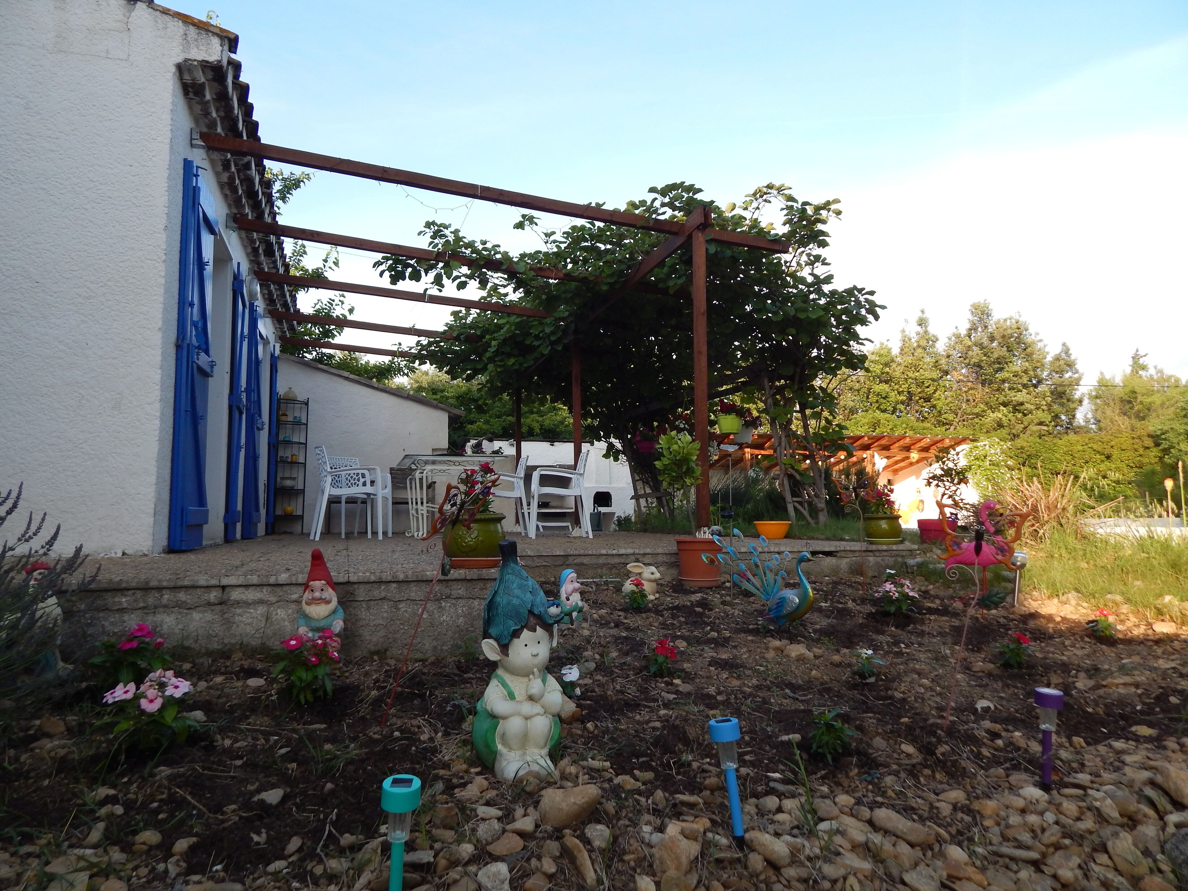 A garden with decorative statues, a pergola, and potted plants.