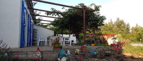 A garden with decorative statues, a pergola, and potted plants.
