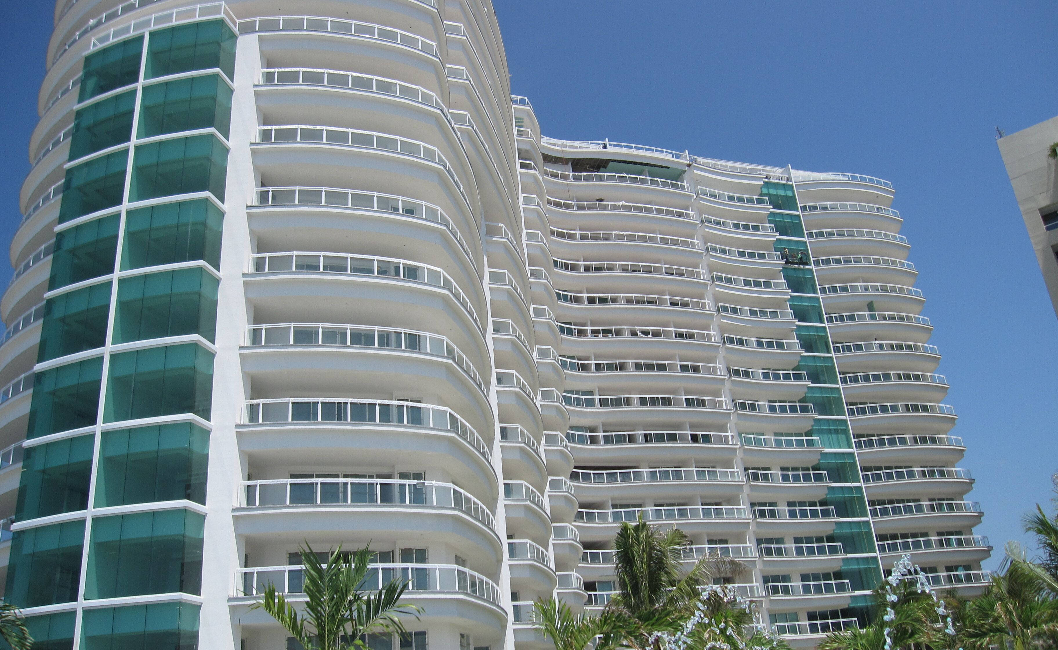 A modern high-rise hotel with multiple balconies and a curved facade.