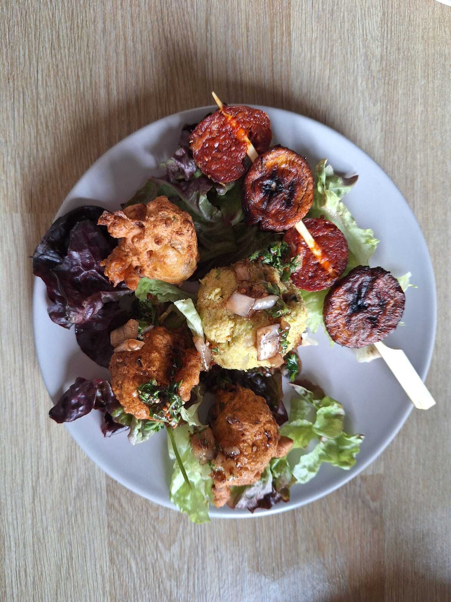Ein Teller mit verschiedenen Speisen, darunter gegrilltes Fleisch, Gemüse und einer Soßenportion.