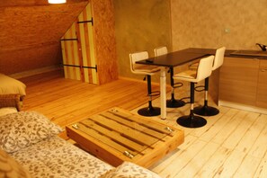A compact room with a wooden dining table and chairs, a small kitchen area, and a bed with patterned bedding. - Studio for 4 people in lively gîte with West Indian delicatessen and activities (Bellechaume)