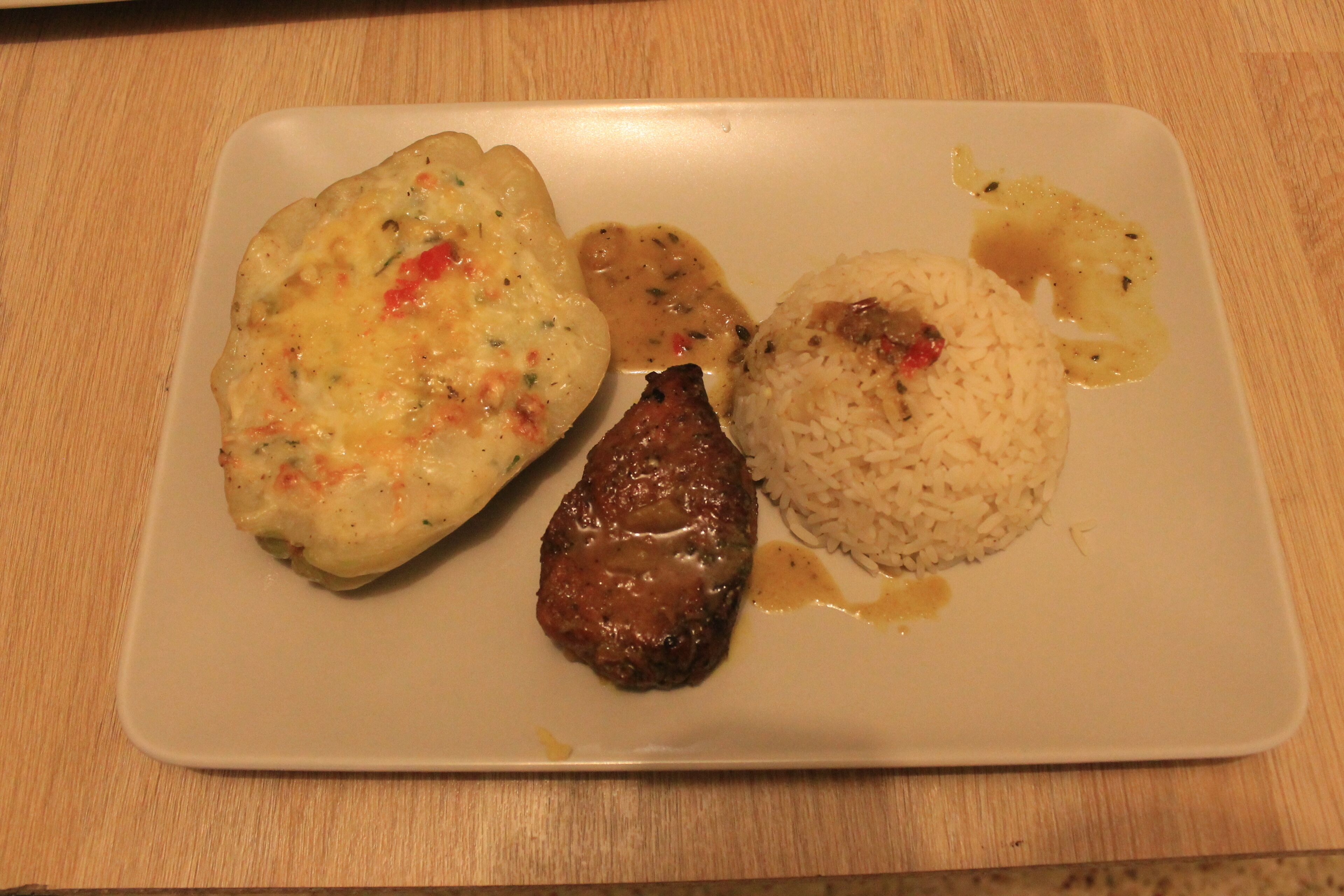 Une assiette contenant un morceau de viande, un plat cuit au four et du riz.