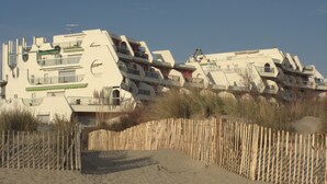 A beachfront property with a unique architectural design, featuring multiple balconies and a sandy beach area.