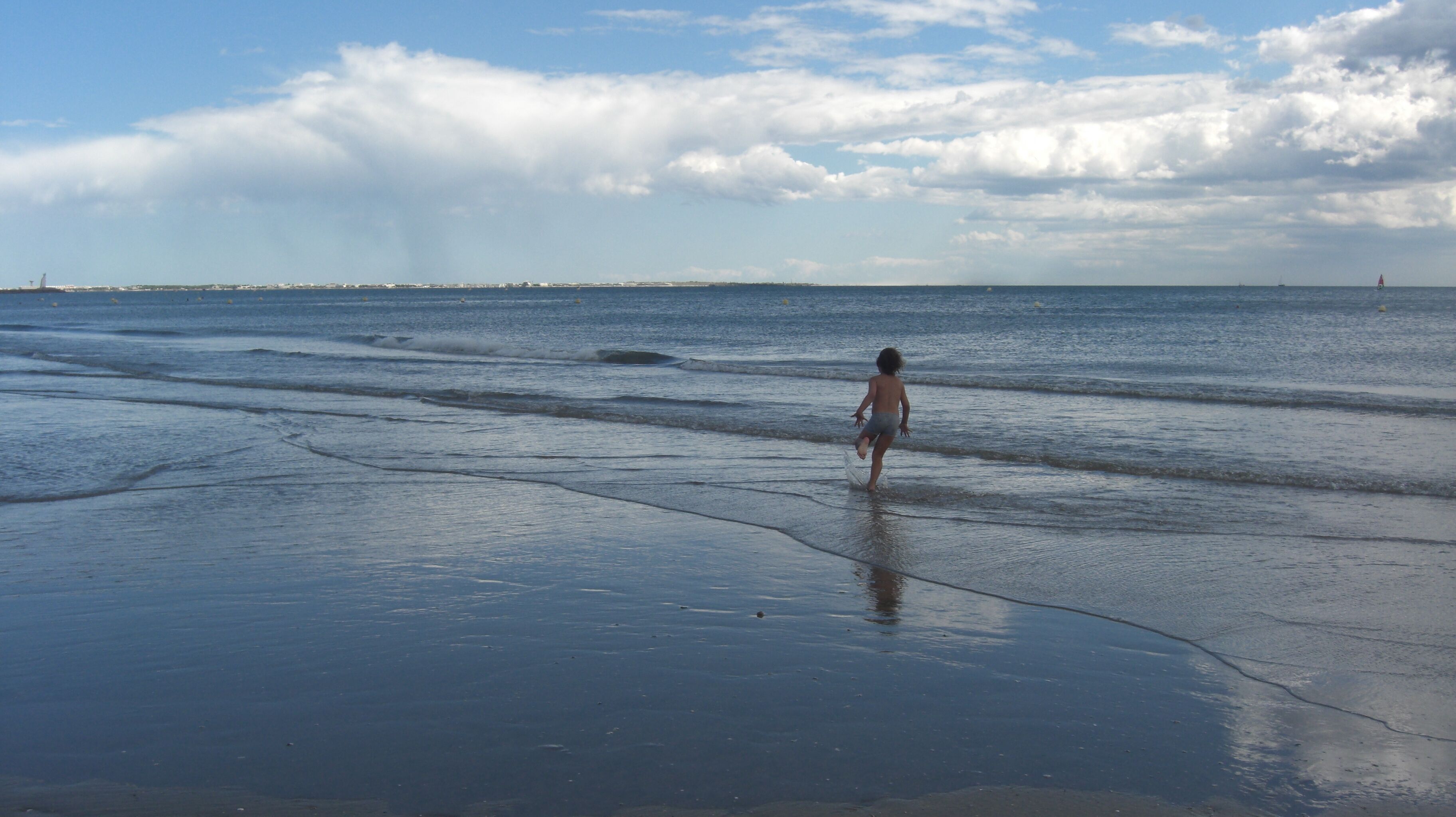 Une plage où l’on voit une personne se promener dans l’eau.