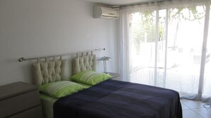 A bedroom with a bed, a nightstand, a lamp, and a window with curtains.