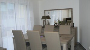 Comedor con una mesa rectangular, seis sillas, un espejo en la pared y una lámpara sobre la mesa.