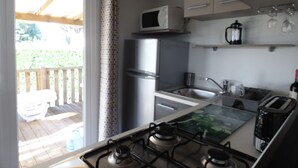 A modern kitchen with a gas stove, microwave, refrigerator, and a sink. - BEAUTIFUL AIR-CONDITIONED MOBILE HOME RENTAL 6-8 PEOPLE LA PALMYRE AUX CHARMETTES 4E (Les Mathes)