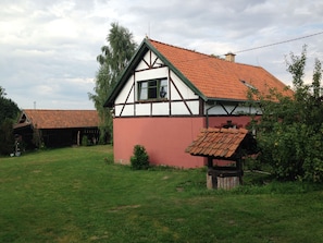 A traditional half-timbered house with a red-tiled roof, surrounded by a grassy yard and trees. - Cosy farmhouse in the masurian countryside (Skowrony)