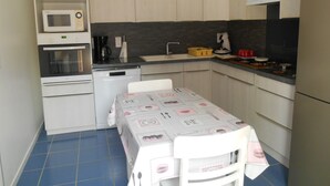 A compact kitchen with a microwave, oven, and dishwasher, a sink, and a table with a tablecloth. - perigourdine house in the countryside (saint germain de belves)