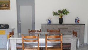 A dining area with a glass-top table, wooden chairs, a potted plant, and a radio on a cabinet. - perigourdine house in the countryside (saint germain de belves)